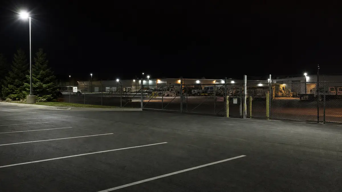 Concept image of an empty commercial parking lot and fenced storage yard at night